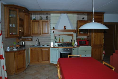 カヴァイオーン・ヴェロネーゼにあるAppartpaolaのキッチン(木製のキャビネット、赤いテーブル付)
