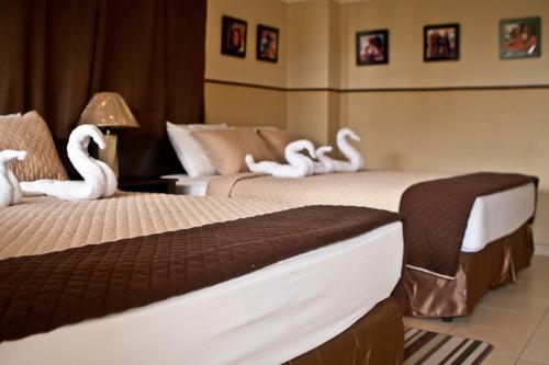 Manglar Lodge في سان كارلوس: سريرين عليها بجعة في غرفة الفندق