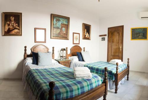 a bedroom with two beds and paintings on the wall at Boutique house LujoPobre in Montilla