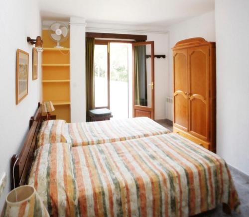 a bedroom with a bed with a striped blanket at Villa Lorenzo in Cala Figuera