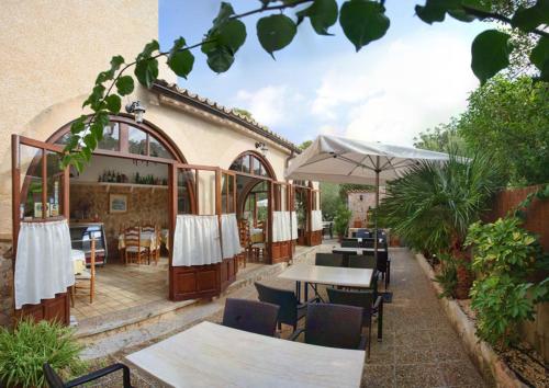 un patio al aire libre con mesas y sillas y un restaurante en Villa Lorenzo, en Cala Figuera