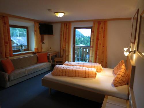 カルス・アム・グロースグロックナーにあるLesacherhofのベッド2台、ソファ、窓が備わる客室です。