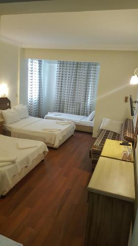a large room with two beds and two windows at Hotel Berlin in Fethiye