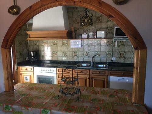 una cocina con un arco sobre un fregadero y una estufa en Apartamentos Turísticos Luar II, en El Rasillo