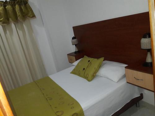 a bedroom with a white bed with a wooden headboard at HOTEL COSTA DEL SOL mav in Turbo