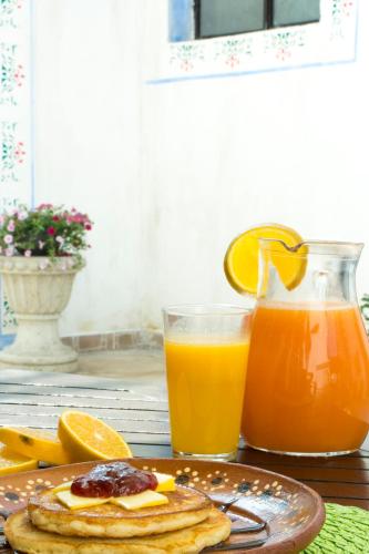 a plate of pancakes with oranges and a glass of orange juice at Hotel & Spa La Mansion del B Azul in Querétaro
