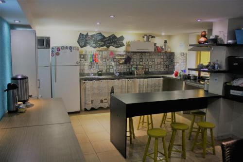a kitchen with a refrigerator and a table and stools at Aurora Hostel Rio in Rio de Janeiro