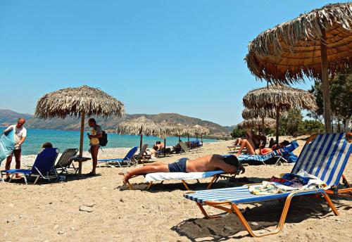 a group of people on a beach with chairs and umbrellas at Camping Mithimna in Kissamos
