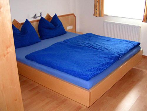 a bed with blue sheets and blue pillows on it at Ferienhaus Beiler in Innsbruck