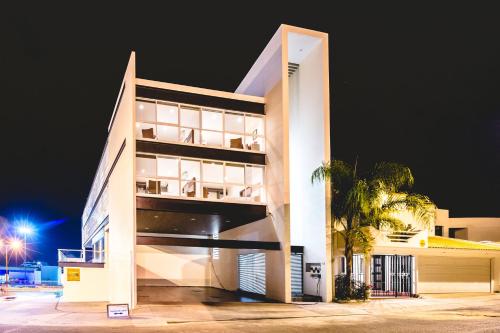 a white building with a palm tree in front of it at Millenium Plaza & Suites in San Luis Potosí