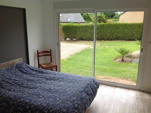 une chambre avec un lit et une porte coulissante en verre dans l'établissement La maison de Brijy, à Pleslin-Trigavou