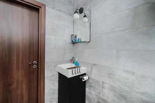 een badkamer met een witte wastafel en een bruine deur bij Sea Crib Apartment in Varna
