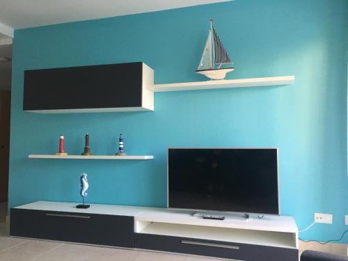 a living room with a tv and a blue wall at Saval Spa Aqquaria Family Complex in Salou