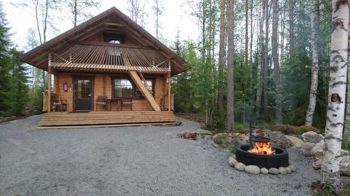 una cabaña de madera en el bosque con una hoguera en Maatilamatkailu Ilomäki en Peräseinäjoki