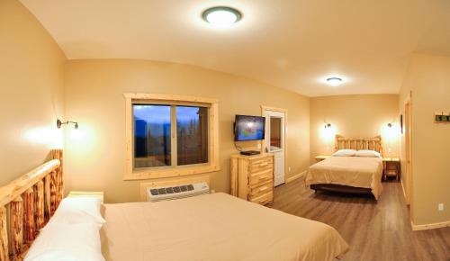 a bedroom with two beds and a tv and a window at Paddle Ridge in West Glacier
