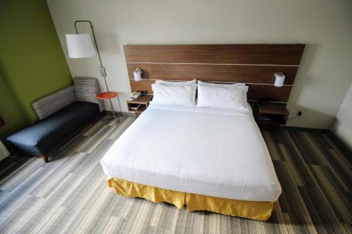 a bedroom with a large white bed and a chair at Holiday Inn Express & Suites Houston - Memorial Park Area by IHG in Houston