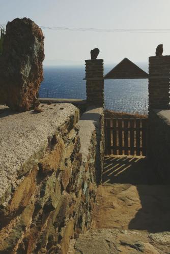 a stone wall with a view of the ocean at Avissalou Apartments in Agios Romanos