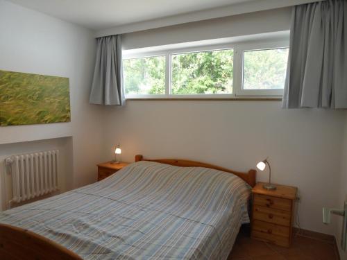 a bedroom with a bed and two windows at Ferienhaus Rücker in Fehmarn