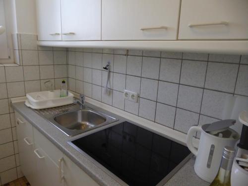 a small kitchen with a sink and white cabinets at Ferienhaus Rücker in Fehmarn
