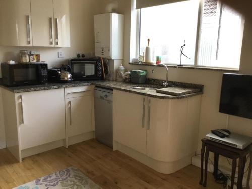 a small kitchen with a sink and a microwave at Canterbury Cottage in Prestatyn