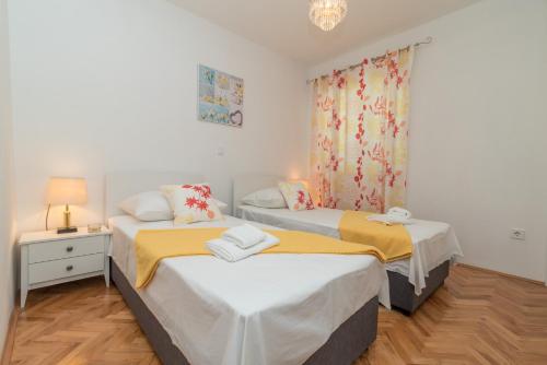 Dos camas en una habitación pequeña con ventana. en New 4* apartment "Orto" in the center of Trogir, en Trogir