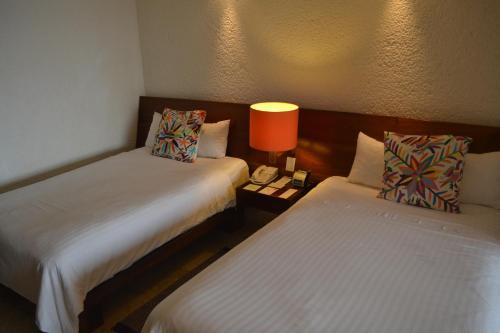 a hotel room with two beds and a lamp at Las Brisas Ixtapa in Ixtapa