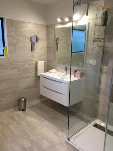 a bathroom with a sink and a glass shower at Kerikeri Garden Homestead in Kerikeri