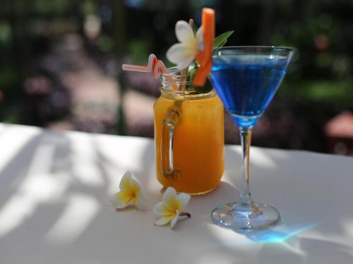 a drink and a glass on a table with flowers at AIRA Boutique Hoi An Hotel & Villa in Hoi An