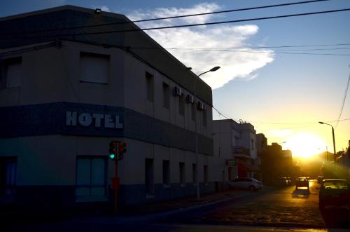 a building on a street with the sunset in the background at Hotel Ro Che Hil Tandil in Tandil