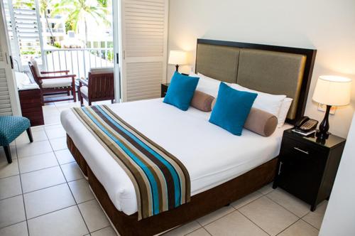 een slaapkamer met een groot bed met blauwe kussens bij 3123 BEACH CLUB PARADISE in Palm Cove