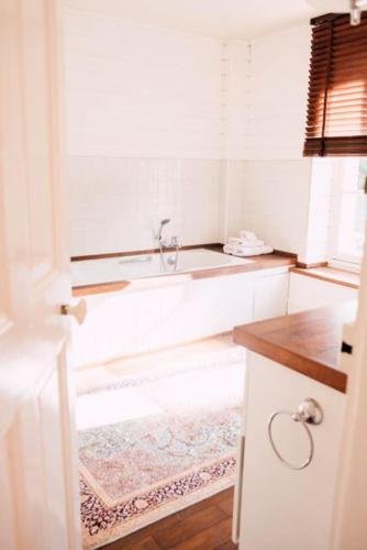 a white bathroom with a sink and a rug at Castel Jolly in Rennes