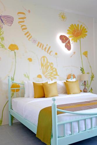 a bedroom with a bed with flowers and butterflies on the wall at Play La Ploen Boutique Resort and Adventure Camp in Ban Nong Khaman
