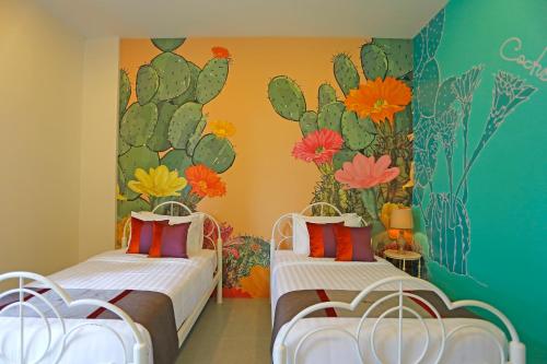 two beds in a room with flowers on the wall at Play La Ploen Boutique Resort and Adventure Camp in Ban Nong Khaman