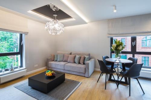 uma sala de estar com um sofá, uma mesa e cadeiras em 7 Heaven - Victoria Residence by OneApartments em Sopot