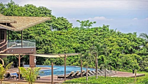 a resort with a swimming pool and trees at Nammbú Beach Front Bungalows in Sámara