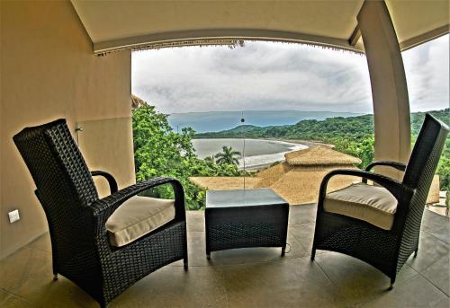 a balcony with chairs and a table and a view of a beach at Nammbú Beach Front Bungalows in Sámara