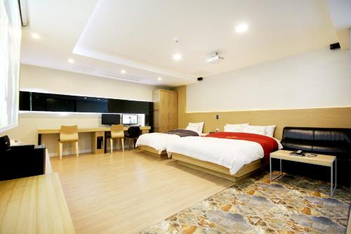 a hotel room with two beds and a desk at No.1 New Yorker Hotel in Jinju