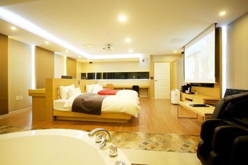 a bedroom with a bed and a tub and a television at No.1 New Yorker Hotel in Jinju