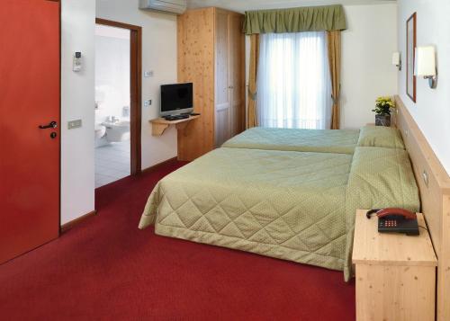ペルジーネ・ヴァルスガーナにあるLa Rotondaのベッドとテレビが備わるホテルルームです。