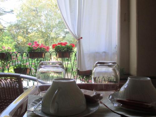 une table avec des assiettes, des verres et une fenêtre dans l'établissement Villa Cantoni, à Gropello Cairoli