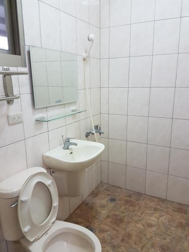 a white bathroom with a toilet and a sink at Ganoun Homestay in Meinong