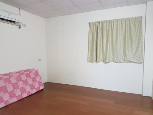 a room with a pink couch and a window at Ganoun Homestay in Meinong