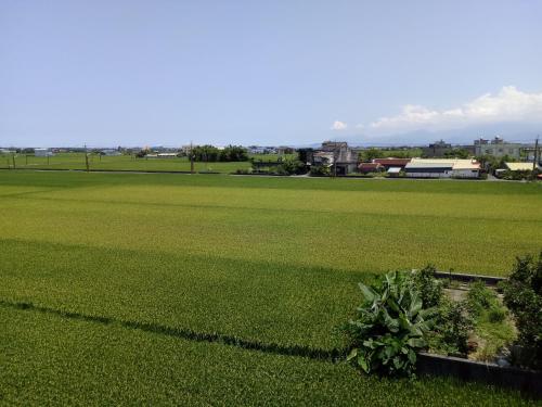 a large field of green grass with a building in the background at Time Travelodge Homestay in Zhuangwei