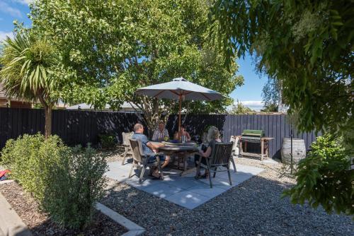 a group of people sitting at a table under an umbrella at Bella Vista Nelson in Nelson