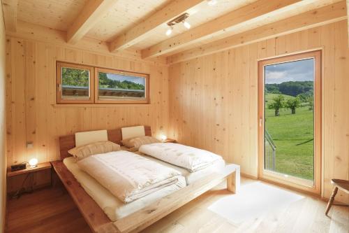 a bed in a wooden room with a large window at Ferienhof Weltenburg in Kelheim