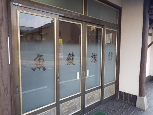 an entrance to a building with chinese writing on the glass doors at Uokagi Ryokan in Nagoya