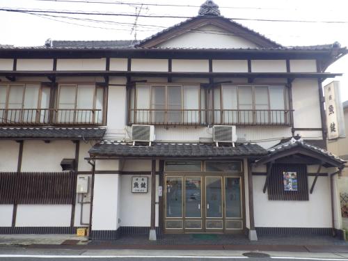 a white building with two balconies and two windows at Uokagi Ryokan in Nagoya