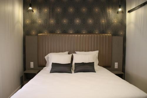 een slaapkamer met een groot wit bed met 2 kussens bij Hotel Saint Vincent in Lyon