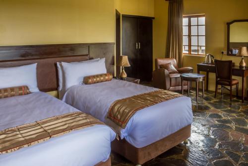 a hotel room with two beds and a desk at Big Valley Game Lodge in Lobatse