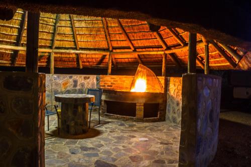 a large stone fireplace in a building with a table at Big Valley Game Lodge in Lobatse